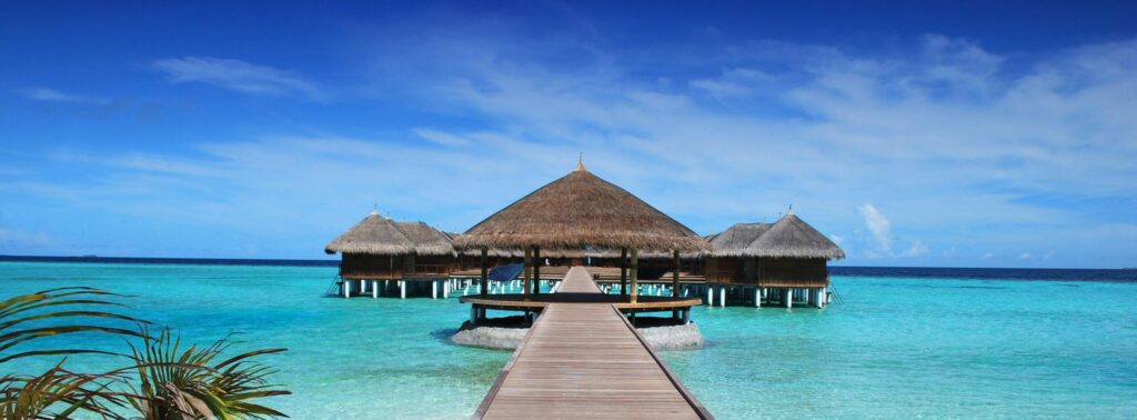 Scenic view of a wooden boardwalk leading to serene overwater bungalows at an island resort.